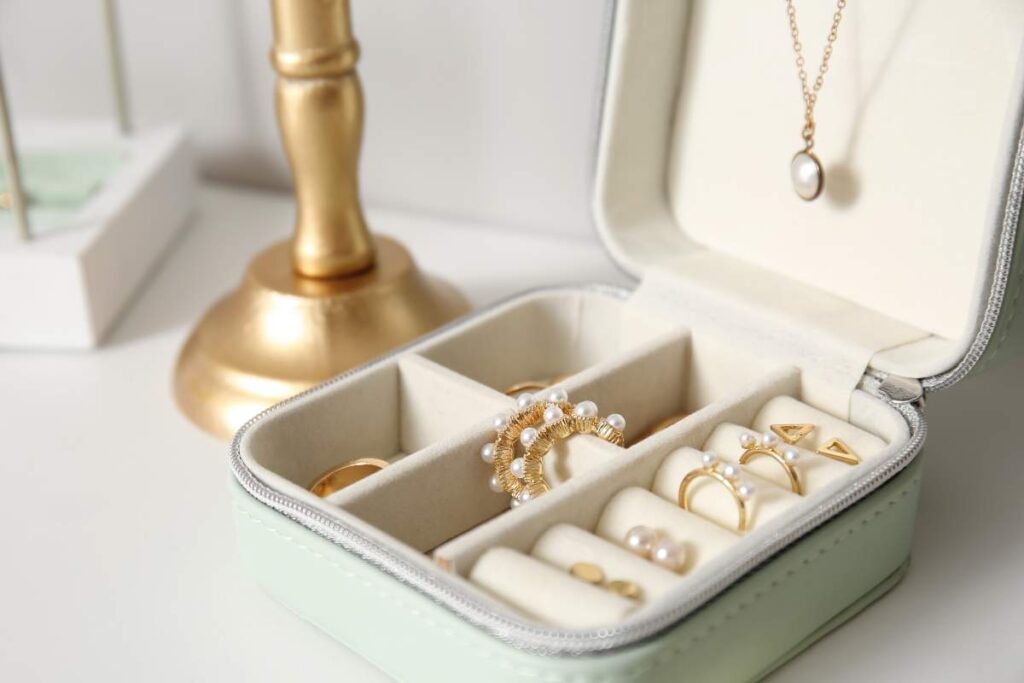 A group of fine jewelry pieces including gold chains, pearl earrings, and gemstone rings displayed on a light fabric.