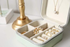 A group of fine jewelry pieces including gold chains, pearl earrings, and gemstone rings displayed on a light fabric.